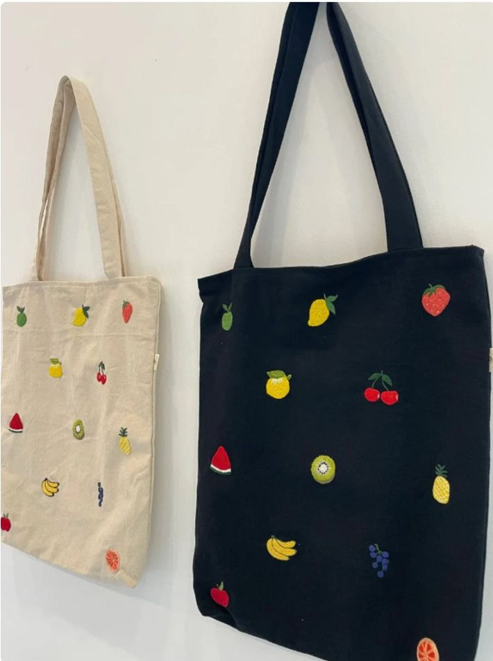 a black and white tote bag with fruit patches on it